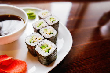 Rolls in nori seaweed with avocado, pickled ginger and soy sauce. Asian cuisine, traditional dish - sushi.