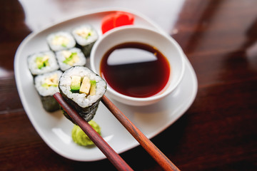 Rolls in nori seaweed with avocado, pickled ginger and soy sauce. Asian cuisine, traditional dish - sushi.