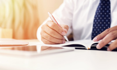 Businessman hands with pen writing on notebook. Selective focus, shallow depth of field.