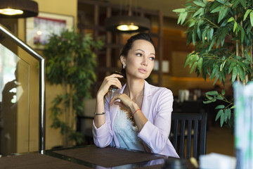 Beautiful woman dreaming about something while sitting with portable net-book in modern cafe bar, young charming female freelancer thinking about new ideas during work on laptop computer