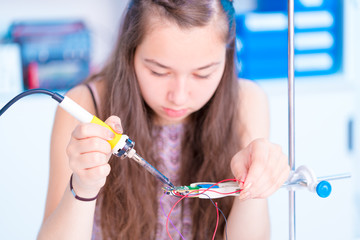 Schoolgirl in electronics class uses a soldering iron