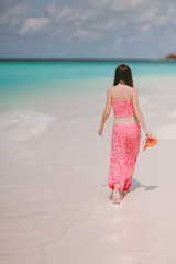 Girl in pink clothes on the beach of the island