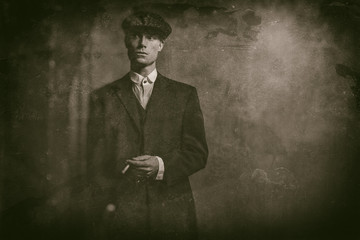 Antique wet plate photo of 1920s english gangster standing with cigarette. Wearing suit and flat cap.
