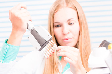 The lab technician examines the results of biochemical tests using a pipette