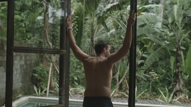 Man stands in the doorway and looks at the pool outside in Bali.