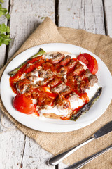 Turkish and Arabic Traditional Ramadan Iskender Adana Kofte Kebab with parsley, bulgur and cheese bread serving on rustic white wood background.