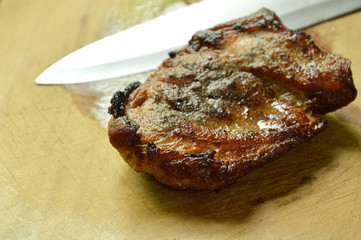 pepper pork steak and knife blade on wooden chop block