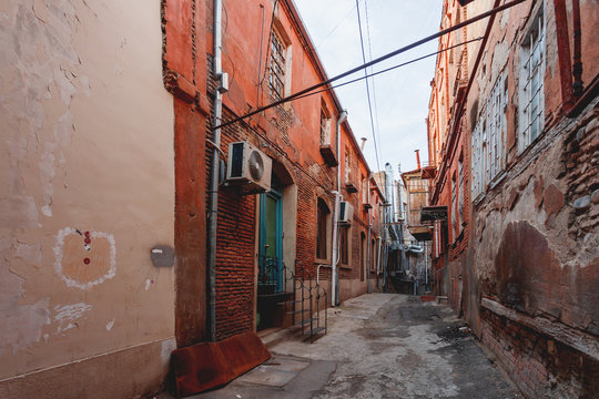 Fototapeta Old narrow street in Tbilisi, Georgia. Old fashioned balconies, wires, red shabby brick buildings.