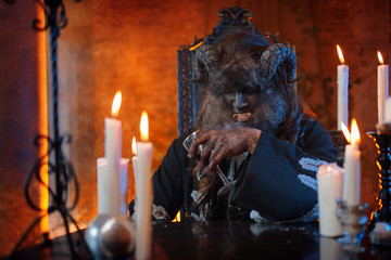man in image of monster with horns sitting at table with a glass in hand, alcohol