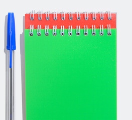 Green and red notepads with pen on table top view