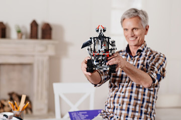 Smiling grandpa examining toy robot