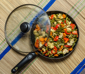 Vegetable stew with meat in a frying pan with lid