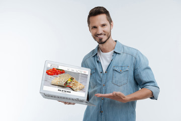 Delighted male person showing web site with food delivery