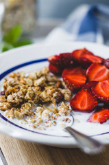 Muesli with milk and fresh strawberry in a white plate