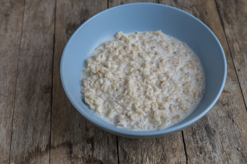 Oatmeal porridge in bowl for breakfast on rustic wooden table