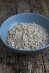 Oatmeal porridge in bowl for breakfast on rustic wooden table
