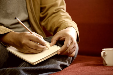 Man hand with pencil writing on notebook.