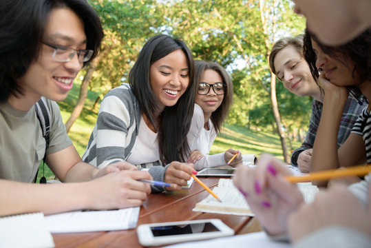Multiethnic group of smiling young students studying