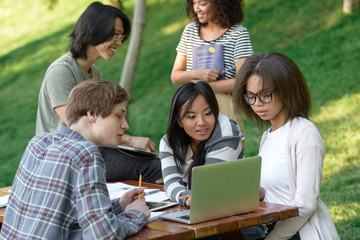 Multiethnic group of happy young students studying outdoors