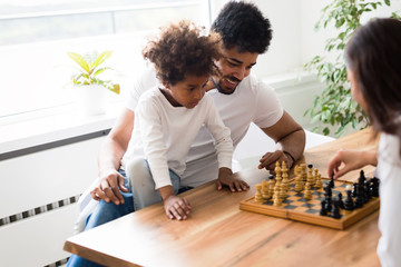 Happy family playing chess together at home
