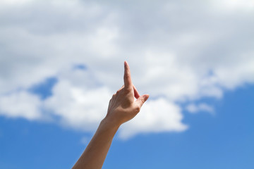 Single female hand with one finger pointing towards blue sky