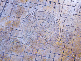 Rosa dei venti e punti cardinali intarsiati in una pavimentazione di un molo