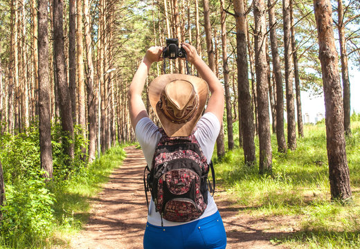 A beautiful girl with a backpack photographing nature, walking in nature, exploring the landscape. The concept of tourism and security.