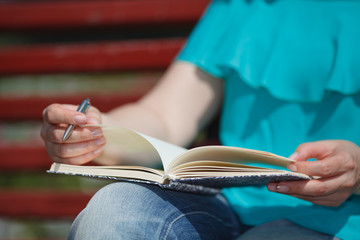 women and education, close up of hands of girl studying for college exam in park. Side view