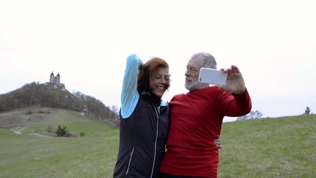 Active senior runners in nature taking selfie with smart phone.