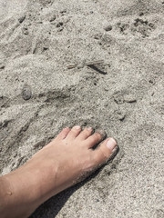 Foot on a sandy beach in summer