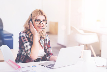 Cheerful call center operator sittign in the office