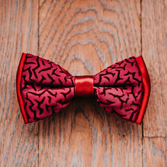 Stylish red bow on wooden background, groom getting ready in morning before the wedding.