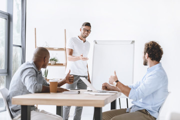 colleagues showing thumbs up while businessman making presentation at meeting