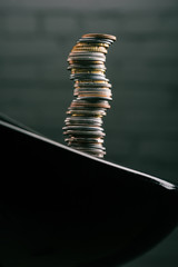 Close up view of stack of different coins standing on edge of table