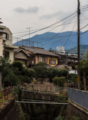  Beautiful scene in a small town in Japan near Kyoto of a river, Japanese houses and blue mountain the background