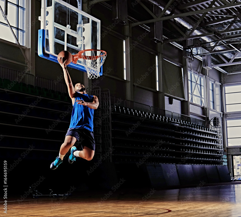 Wall mural black professional basketball player in action on a basketball field.