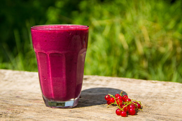 Glass of berry smoothie on wooden table on blurred background