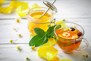 A healthy Cup of tea, a jar of honey and flowers. Selective focus.