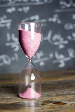 Hourglass on wood with a blackboard background