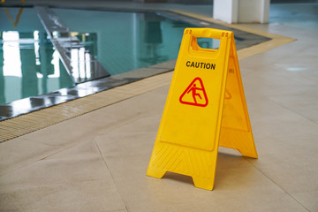 caution wet floor warning sign near swimming pool