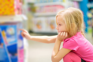 Adorable girl in pink explore toys in kids supermarket