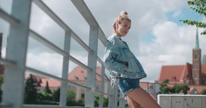Pretty fashion woman in a city in Europe. Happy stylish girl wearing denim jacket enjoying time during sunny day.