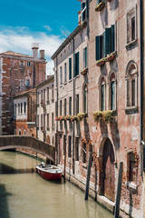 Fototapeta na wymiar View on a venetian canal with ancient buildings and bridge in Venice