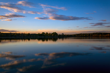 Fototapeta na wymiar Smooth surface of lake at sunset