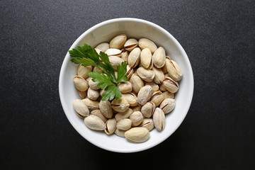 pistachio nuts in a bowl on black background
