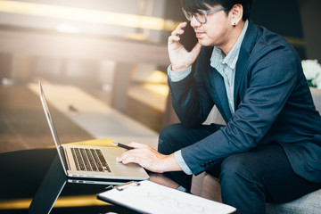 Handsome businessman in suit and eyeglasses speaking on the phone in office,Side view shot of a...