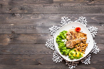 Pork steak homemade cooking with spices leaves lettuce on wooden cutting board, and a dish,