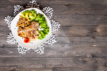 Pork steak homemade cooking with spices leaves lettuce on wooden cutting board, and a dish,
