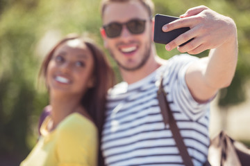 selective focus of young happy multiethnic couple taking selfie on smartphone