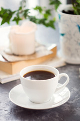 Morning cup of coffee with a book, berries, cakes and candle. Romantic brekfast